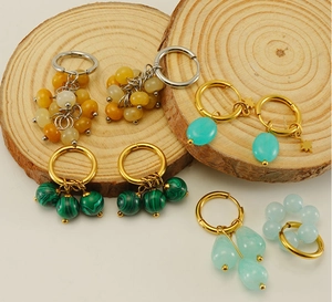 Detail of 18k gold earrings with malachite and natural stone beads on wood