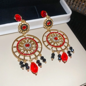 Détail de boucles d'oreilles bohèmes vintage avec cristaux rouges et métal doré ajouré