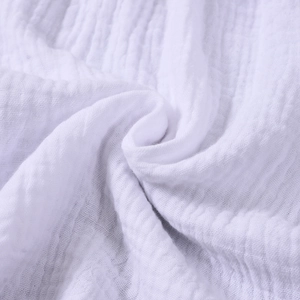 Close-up of white crepe cotton fabric showing soft wrinkled texture and breathable gauze