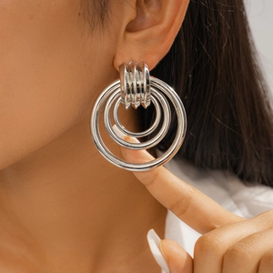 Close-up of a model wearing silver multi-loop geometric circular drop earrings with metal finish