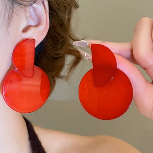 Detail shot of large red geometric acrylic earrings featuring a glossy reflective finish