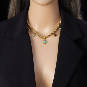 Golden tree of life and turquoise clover necklace displayed on a black blazer