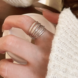 Macro detail of silver multi-layered stacked ring worn with elegant white sweater sleeve