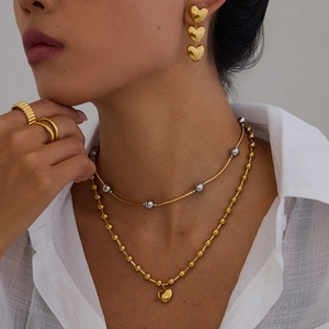 Collier multicouche avec pendentif cœur, boucles d'oreilles et bagues dorées sur modèle