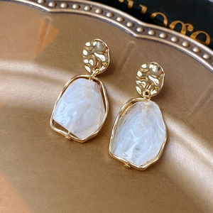 Détail macro de boucles d'oreilles vintage en résine sur plateau en métal doré