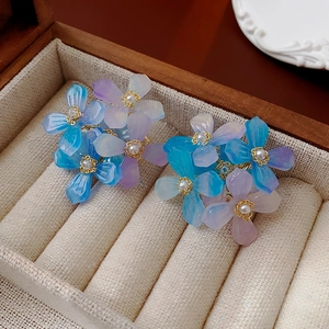 Détail de boucles d'oreilles fleurs en acrylique et perles dans un écrin en bois