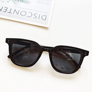 Detailed top view of black rectangular sunglasses with silver metal rivets on white surface