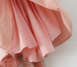 Detailed view of pink pleated multi-layer skirt with silky texture and soft drape