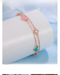 Detail of rose gold double-layer silver bracelet with pink enamel heart and zircon