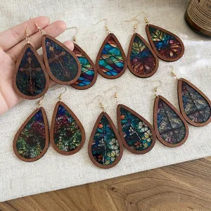 Ethnic teardrop earrings with wood frame and colorful printed patterns on linen background