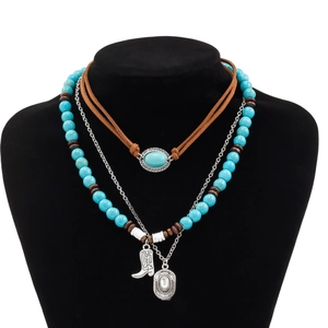 Detail of layered turquoise beaded necklace with silver western boot and hat charms