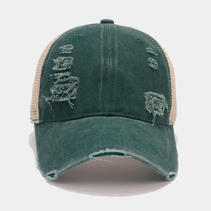 Close-up of distressed ripped details on washed green cotton and mesh baseball cap