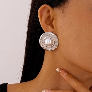 Detail of silver hammered metal round earring with large pearl on model ear