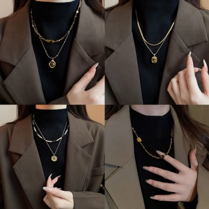 Layered gold necklace featuring oval tiger eye stone pendant on brown blazer model