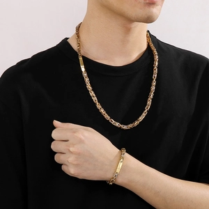 Détail d'un ensemble collier et bracelet en chaîne byzantine dorée porté par un homme