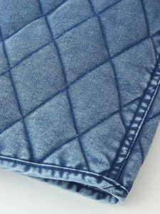Macro shot of blue washed denim fabric with diamond quilted pattern and thick stitching