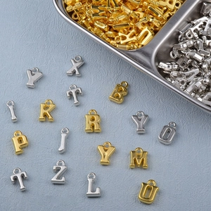 Flat lay of gold and silver metal alphabet letter charms for DIY jewelry making