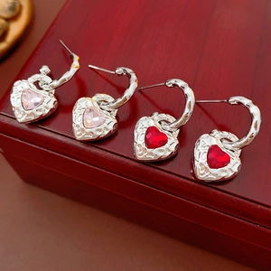 Detail of silver C-shape earrings with vintage textured pink and red crystal hearts