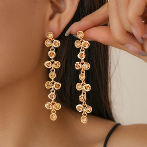 Boucles d'oreilles pendantes dorées avec fleurs en cristal portées par un mannequin