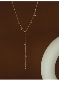 Artistic close-up of 18k gold-plated Y-shaped necklace with beads on minimalist backdrop