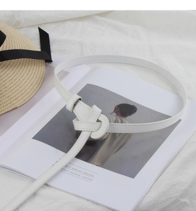 Detailed view of white leather thin belt with stitching and decorative knot styling