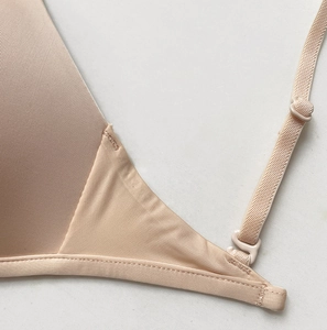 Close-up of seamless stitching on a beige triangle bra strap buckle and side wing