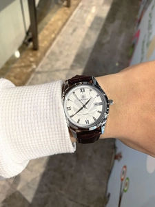 Wrist shot of quartz watch with silver case, white dial and brown leather strap