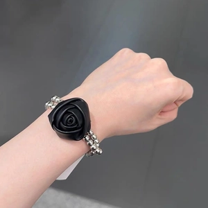 Bracelet à perles argentées avec une rose noire en similicuir au poignet