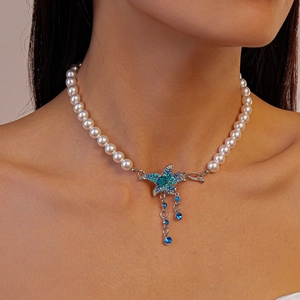 Macro shot of pearl necklace with blue crystal starfish pendant and silver tassels