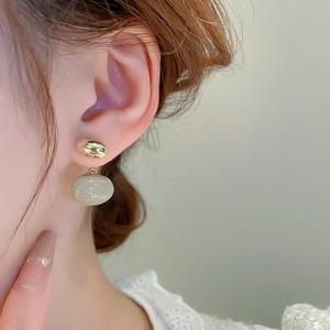 Gros plan de boucles d'oreilles ovales dorées avec pendentifs en résine grise