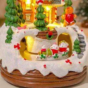 Close-up of lit resin Christmas gingerbread candy shop with snow texture and mini train
