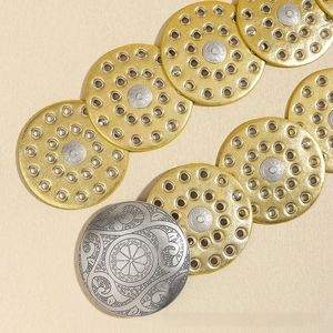 Macro detail of western-style engraved metal conchos for bohemian decorative belts