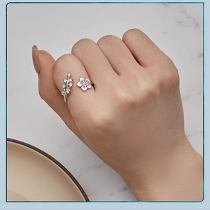 Detail of an adjustable 925 silver ring with pink cherry blossom and diamond leaf petals