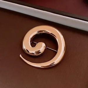 Minimalist golden spiral brooch with polished metallic finish for a luxury fashion look