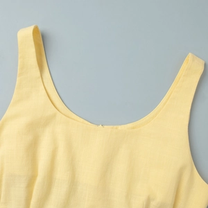 Gros plan sur la texture en coton lin jaune et les coutures du col en U du haut sans manches