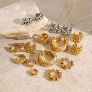 Dettaglio di vari ear cuff in acciaio inox oro e argento su base in pietra neutra