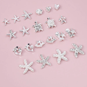 Silver ocean theme nail charms set with rhinestones and pearls on pink background