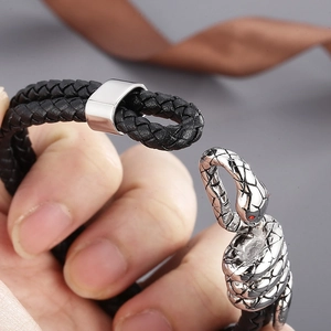 Macro detail of men's leather bracelet showing silver snake head clasp with red stone eyes
