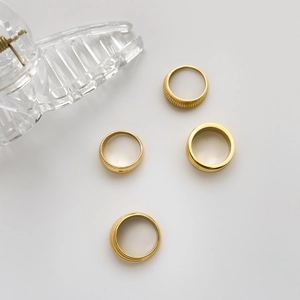 Detail showing four gold textured and smooth stacked rings on a clean white backdrop