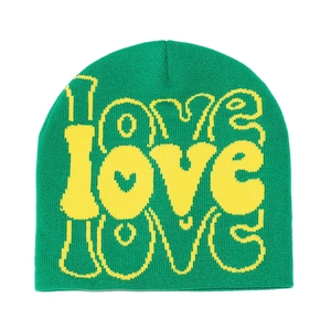 Close-up of green knit beanie featuring a yellow LOVE jacquard pattern and heart detail