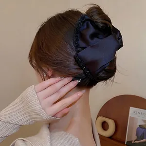 Elegant large black satin bow hair claw clip with delicate sequins in a half-up hairstyle