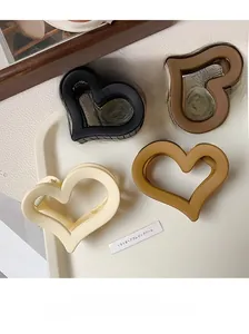 Detailed view of four heart-shaped matte shark clips in neutral tones on a display tray