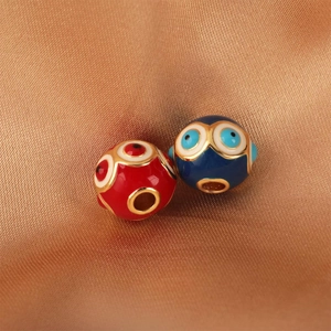 Macro detail of red and blue enamel evil eye beads on gold silk for DIY jewelry making