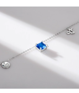 Macro shot of silver Capricorn necklace with blue square gemstone and engraved round charms