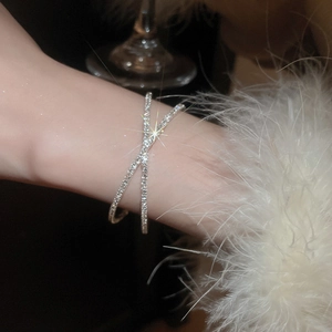 Close-up of sparkling crisscross diamond bangle with pearls on model wrist