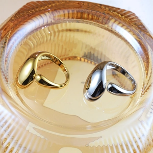 Polished stainless steel waterdrop rings in gold and silver set on amber glass tray