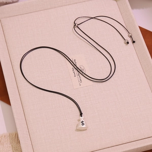 Macro shot of white money bag pendant with dollar sign on adjustable black cord necklace