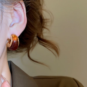 Detailed view of amber resin C-shape earrings with 18k gold plating on model