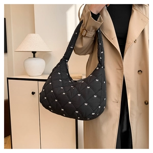 Detail der schwarzen Stepptasche mit weißen Schleifen-Stickereien auf Nylon-Oberfläche