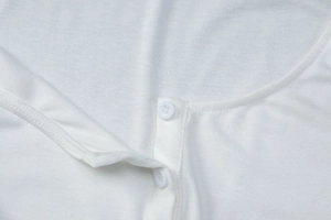 Détail de l'encolure en maille côtelée avec boutons blancs de cette robe moulante
